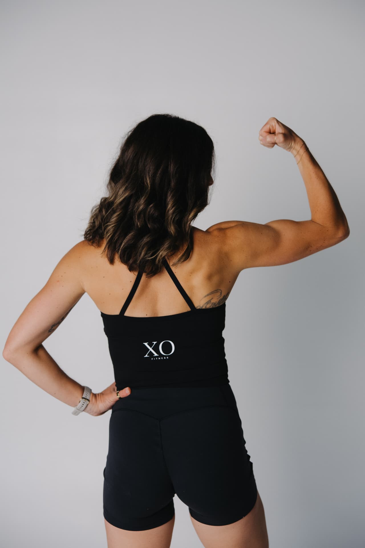 Lauren flexing in an XO Fitness tank
